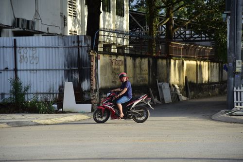 Free Motorcyclist waiting on a city street corner with afternoon shadows. Stock Photo