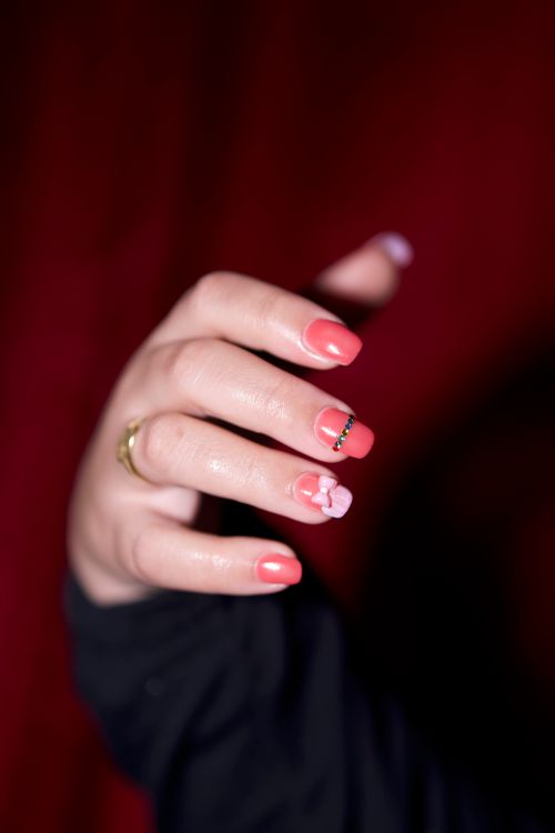 Free A detailed close-up of manicured nails with pink polish and floral accents, set against a dark background. Stock Photo