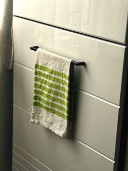 Green striped kitchen towel on a sleek white cabinet in a cozy Romanian kitchen.