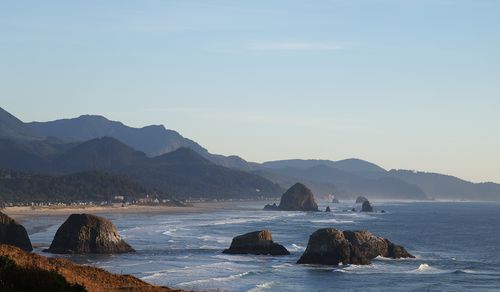 Free A stunning coastal view of Cannon Beach featuring Haystack Rock and surrounding mountains. Stock Photo