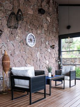 Stylish outdoor seating area with stone wall, stylish decor, and natural lighting. - Fotografer Sidoarjo