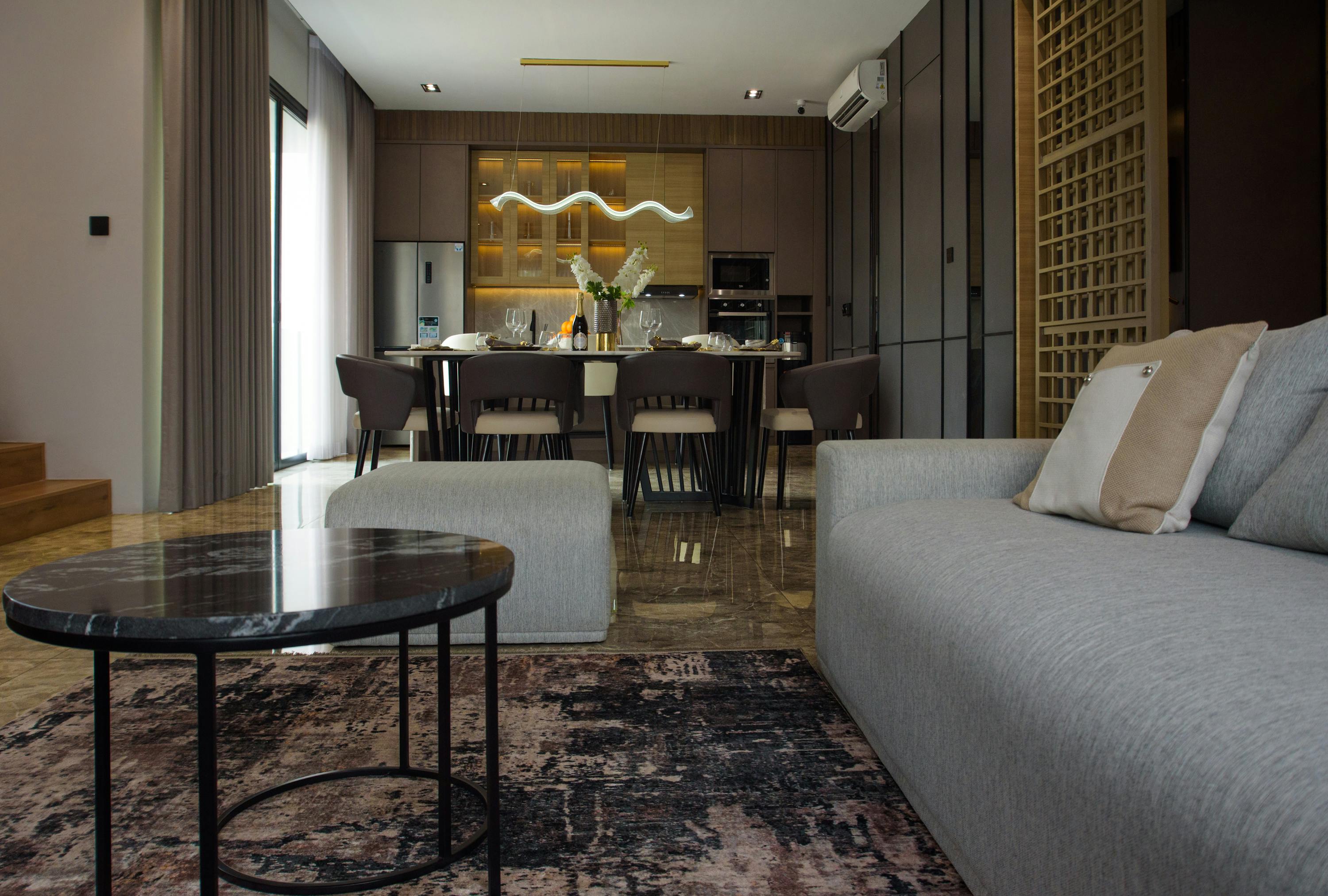 Esstisch im Wohnzimmer mit Teppich, Stuehlen und Sideboard als klare Esszone