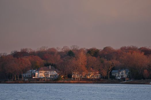 Picturesque fall scene of waterfront homes surrounded by autumn foliage at twilight in Stamford, Connecticut.