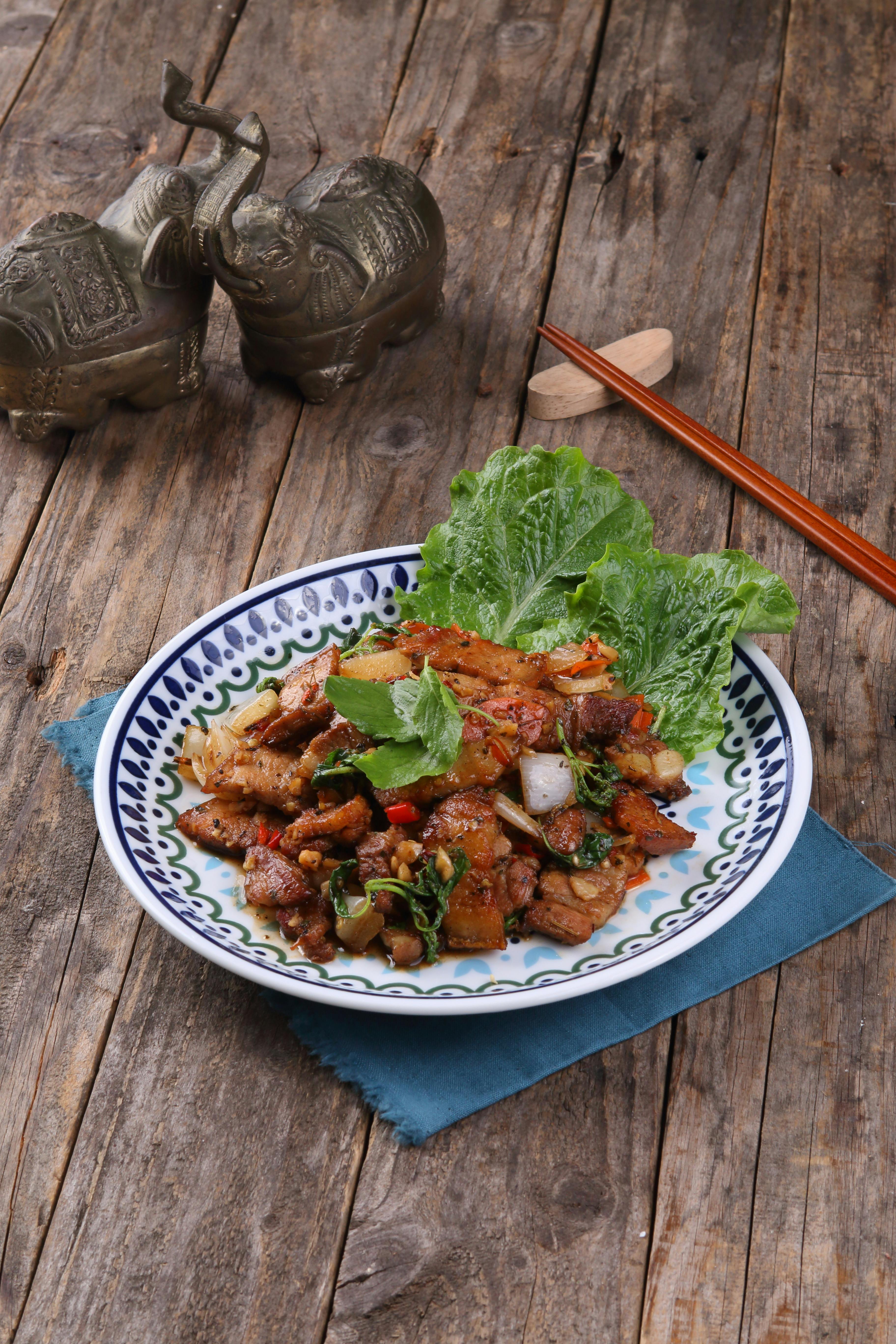 Flavorful Asian stir-fry with herbs on a rustic wooden table, plated beautifully.