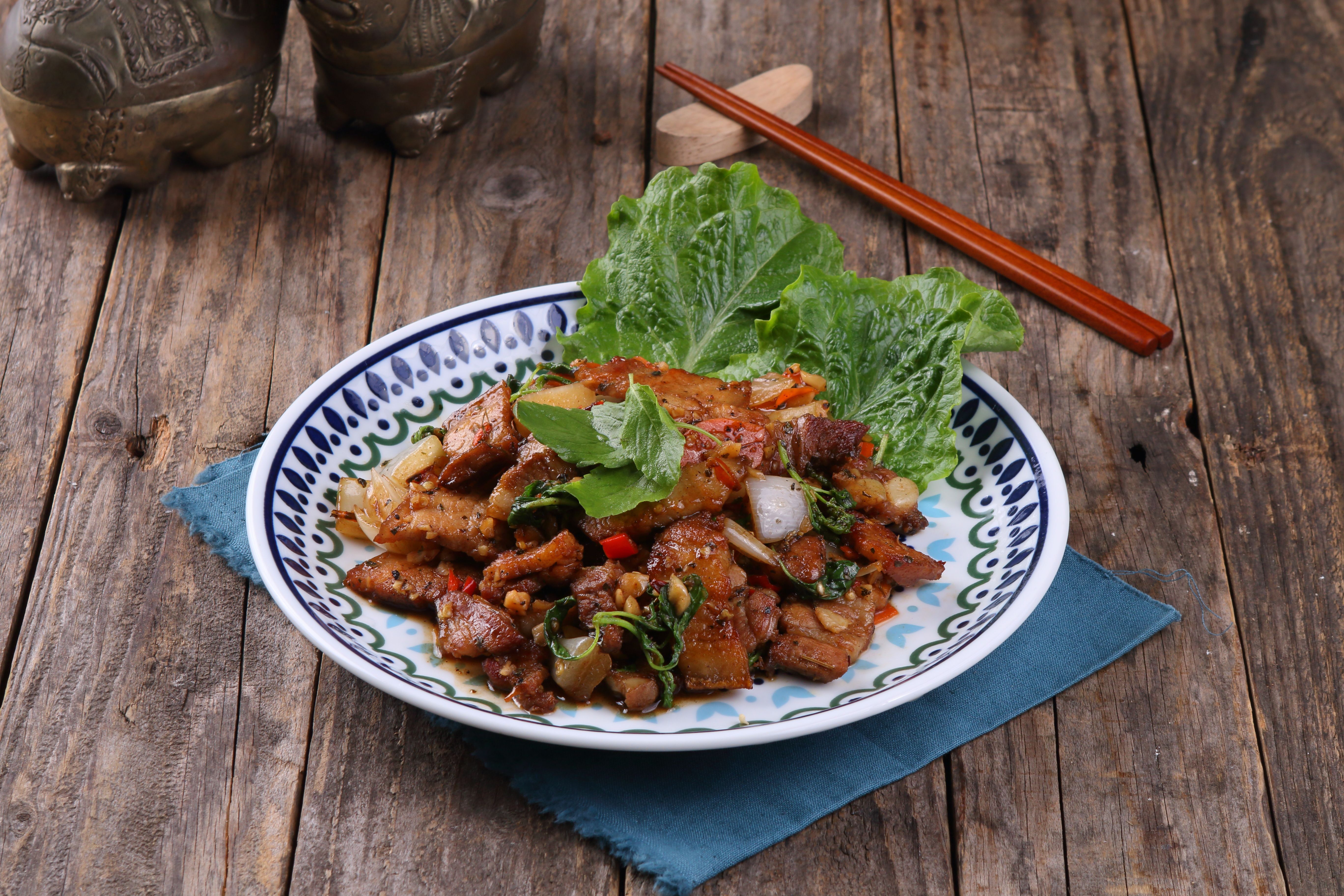 An appetizing Asian stir-fry dish with vegetables on a rustic wooden table.