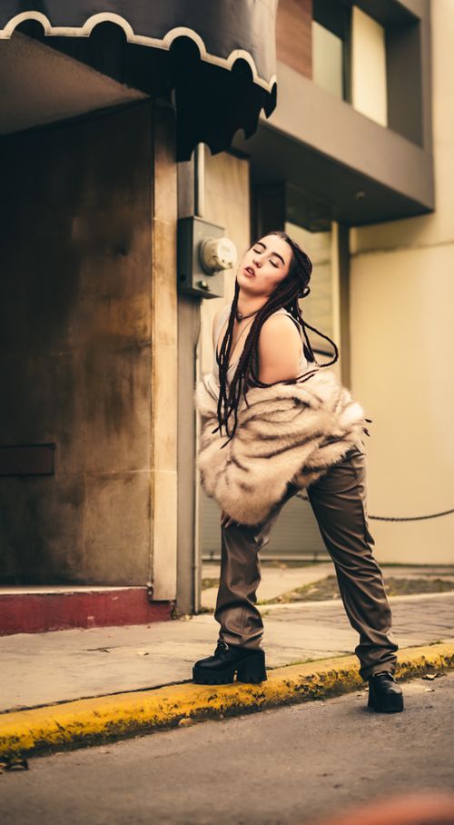 Free Stylish individual posing in city street wearing a fur coat. Stock Photo