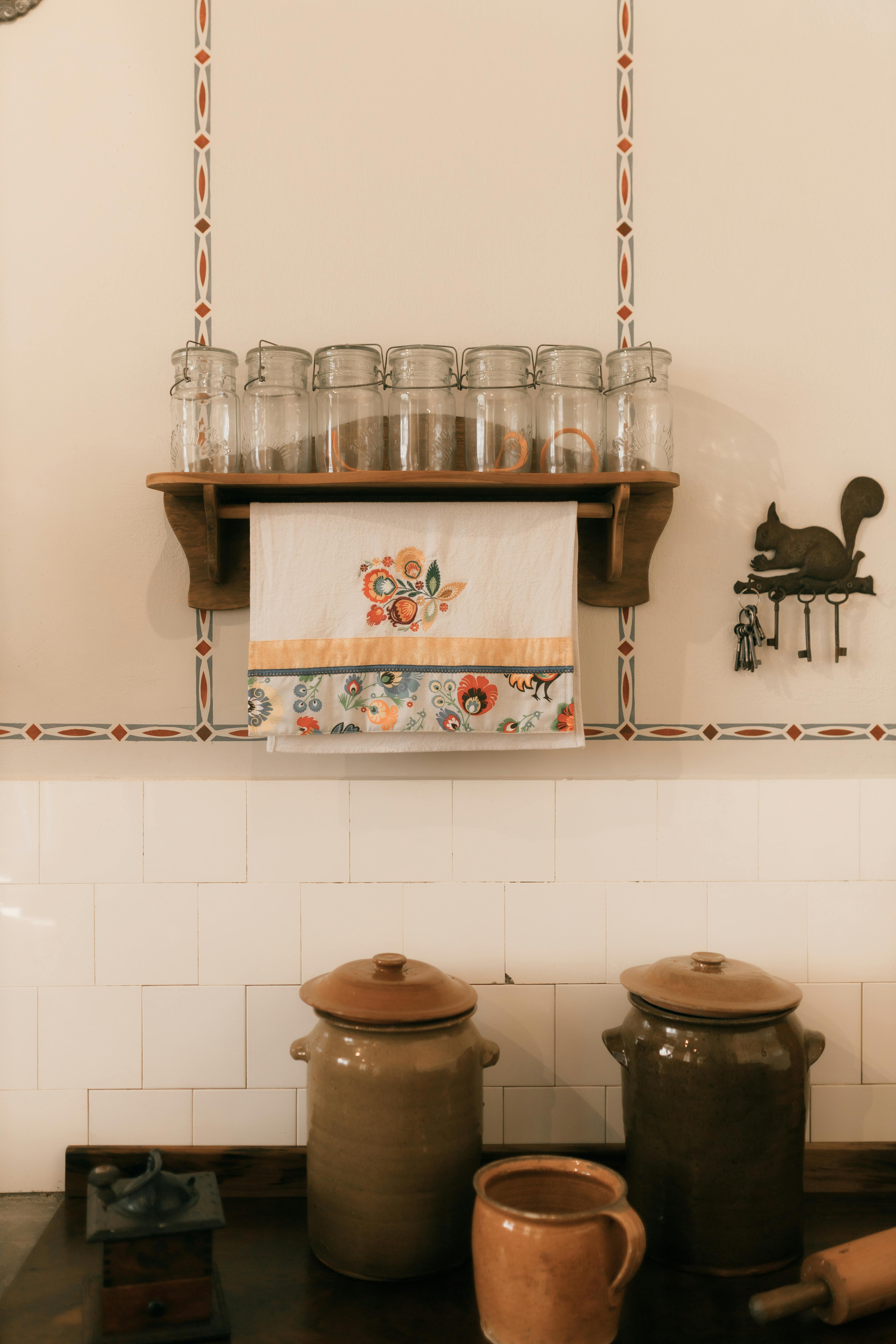 Warm rustic kitchen scene with ceramic jars and decorative elements on a wooden shelf.