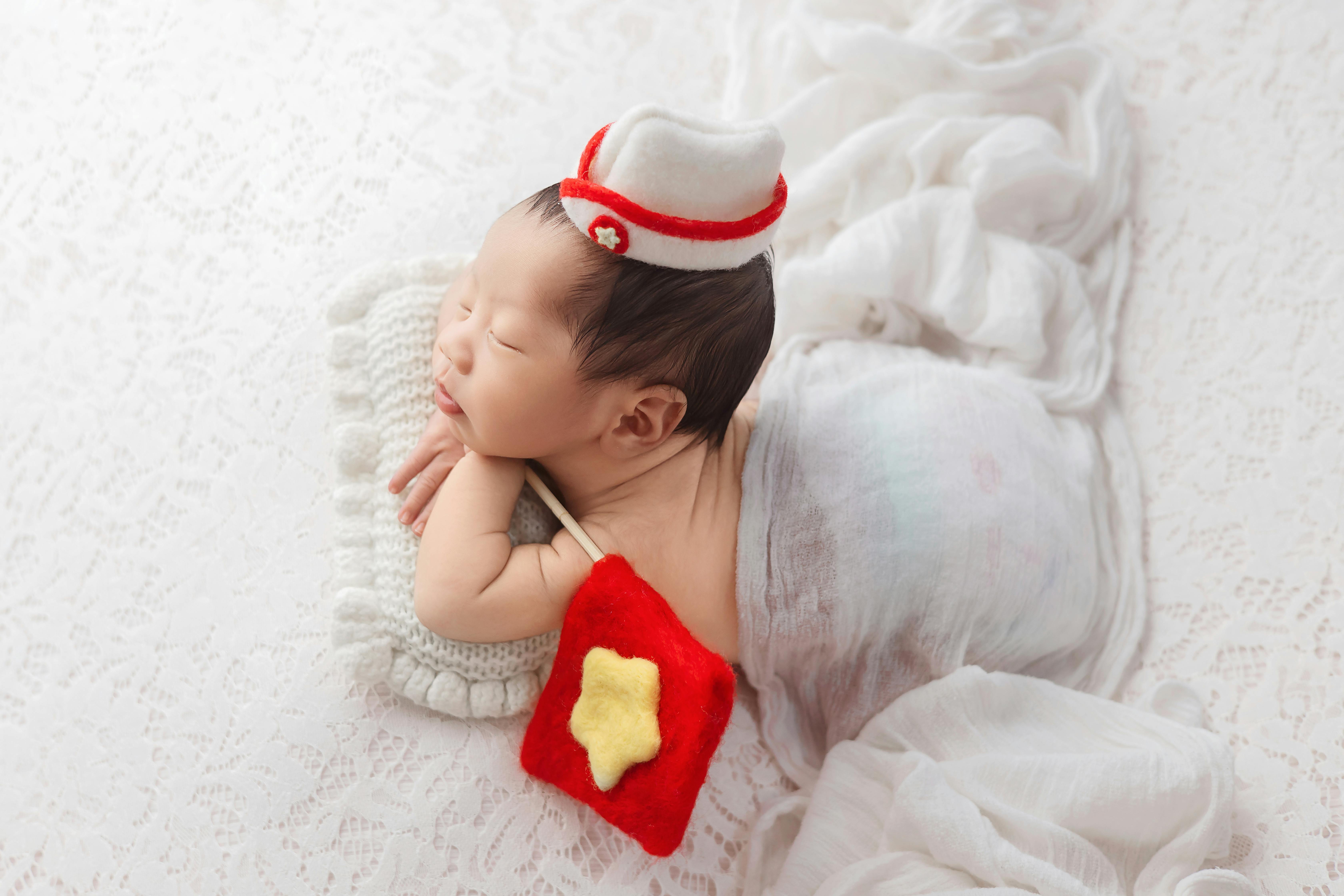 Adorable newborn sleeping in a Vietnamese-inspired outfit with a star pillow, taken in Ho Chi Minh City studio.