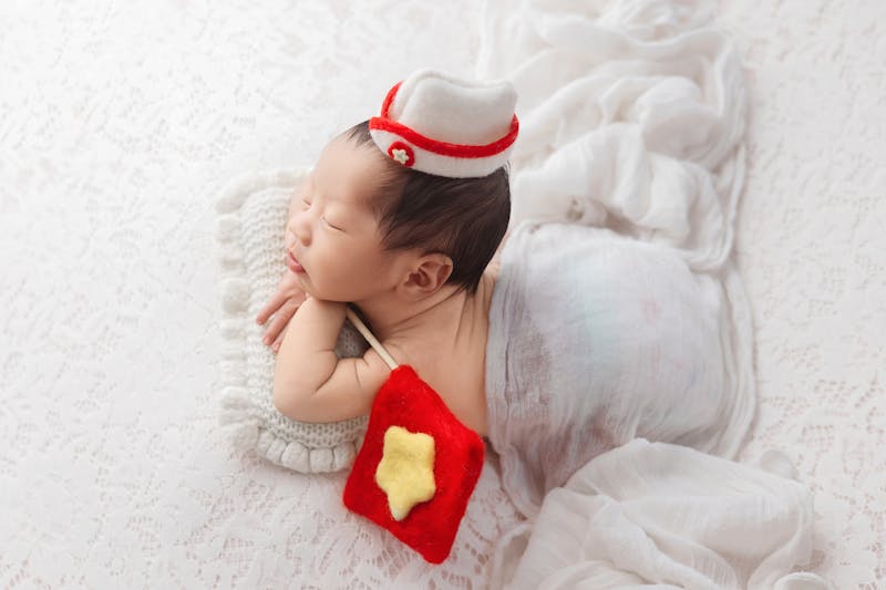 Adorable newborn sleeping in a Vietnamese-inspired outfit with a star pillow, taken in Ho Chi Minh City studio.