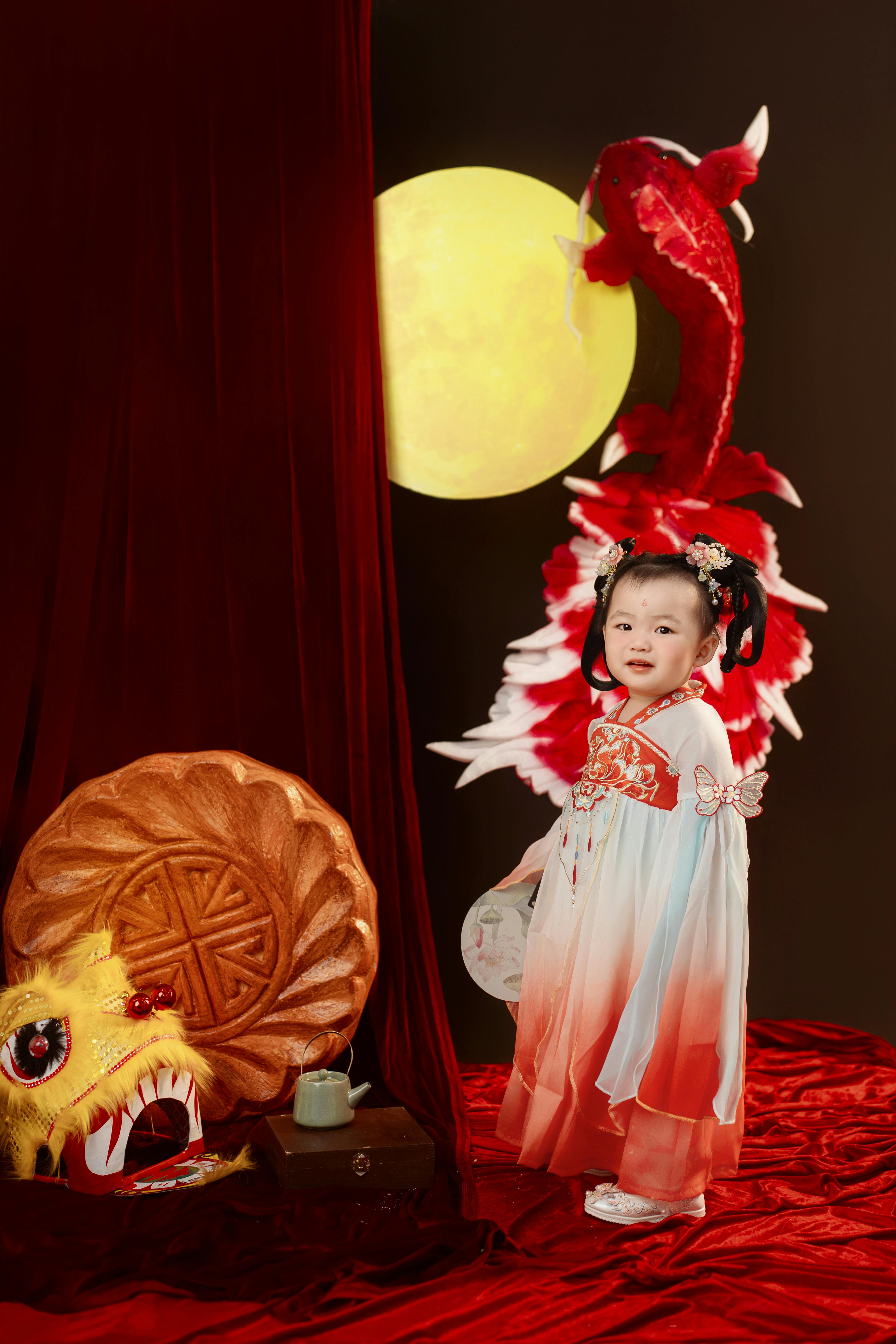 Charming child in ao dai with dragon backdrop, celebrating Vietnamese festival.