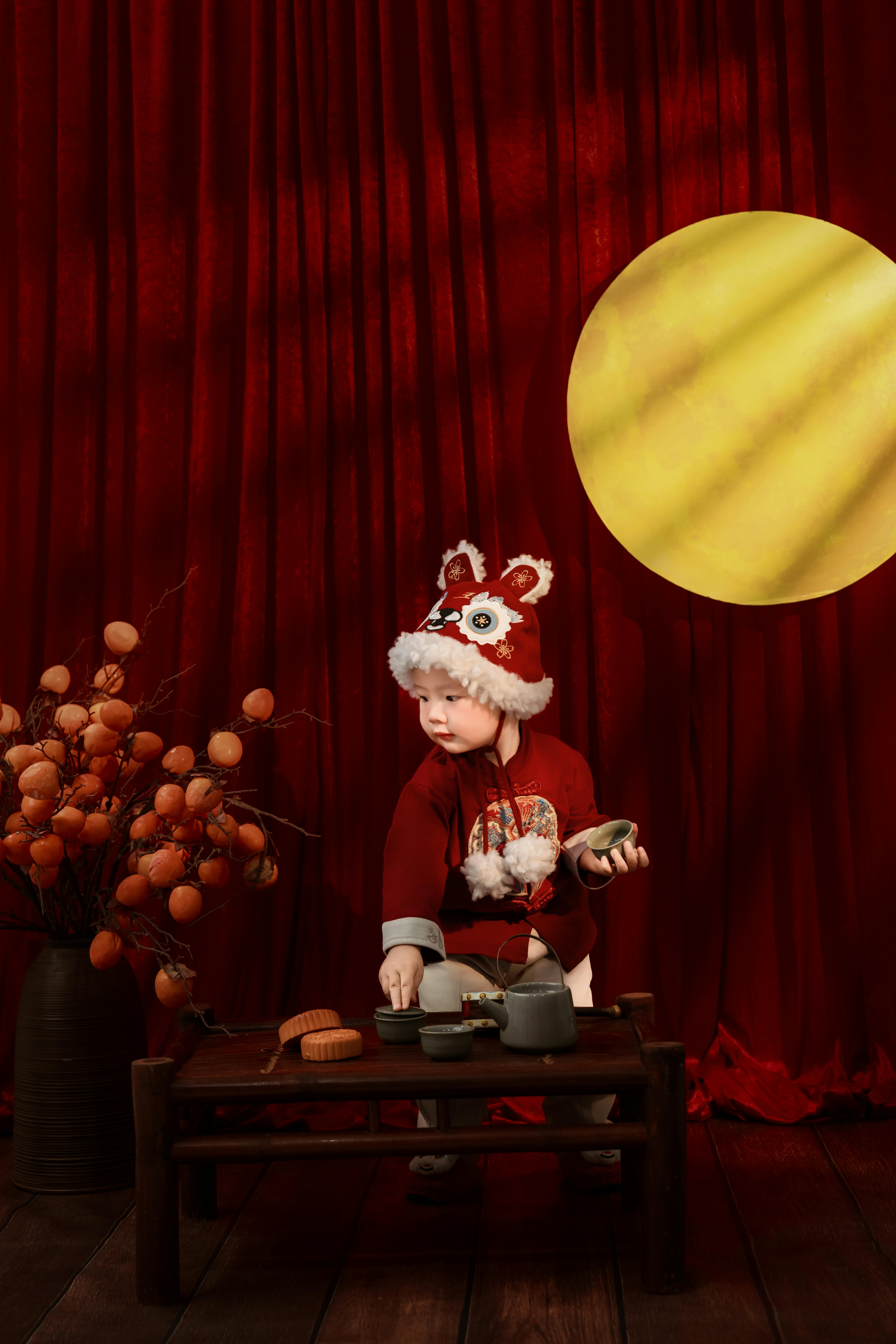 Adorable baby in traditional red outfit with dragon hat, celebrating in Ho Chi Minh City, Vietnam.