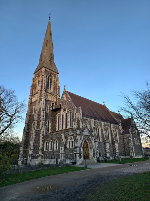 Free A picturesque Gothic Revival church under a clear blue sky during sunset. Stock Photo