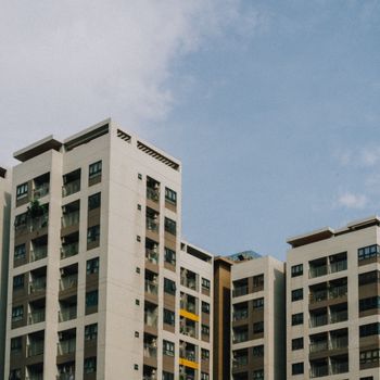 High-rise apartment buildings with balconies under a bright blue sky, showcasing urban architecture.