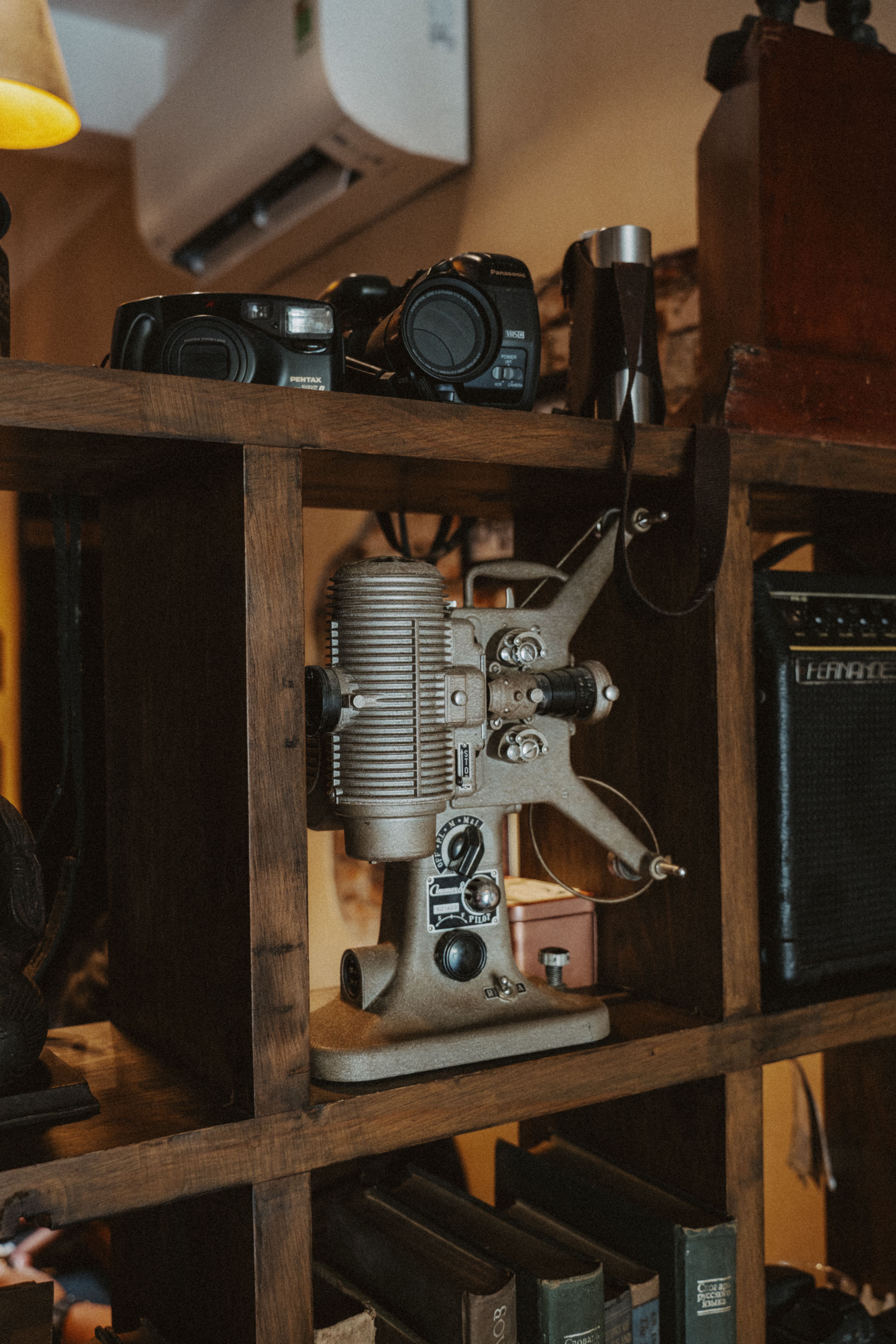 Old film projector and retro cameras on a wooden shelf, giving a nostalgic feel to a cozy setting.
