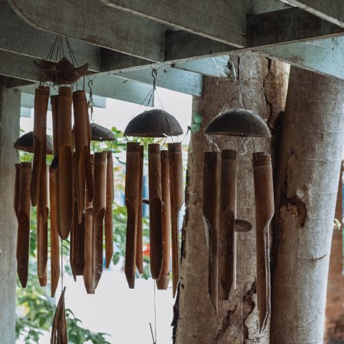 Free Charming bamboo wind chimes hang under a wooden structure with natural light filtering through. Stock Photo