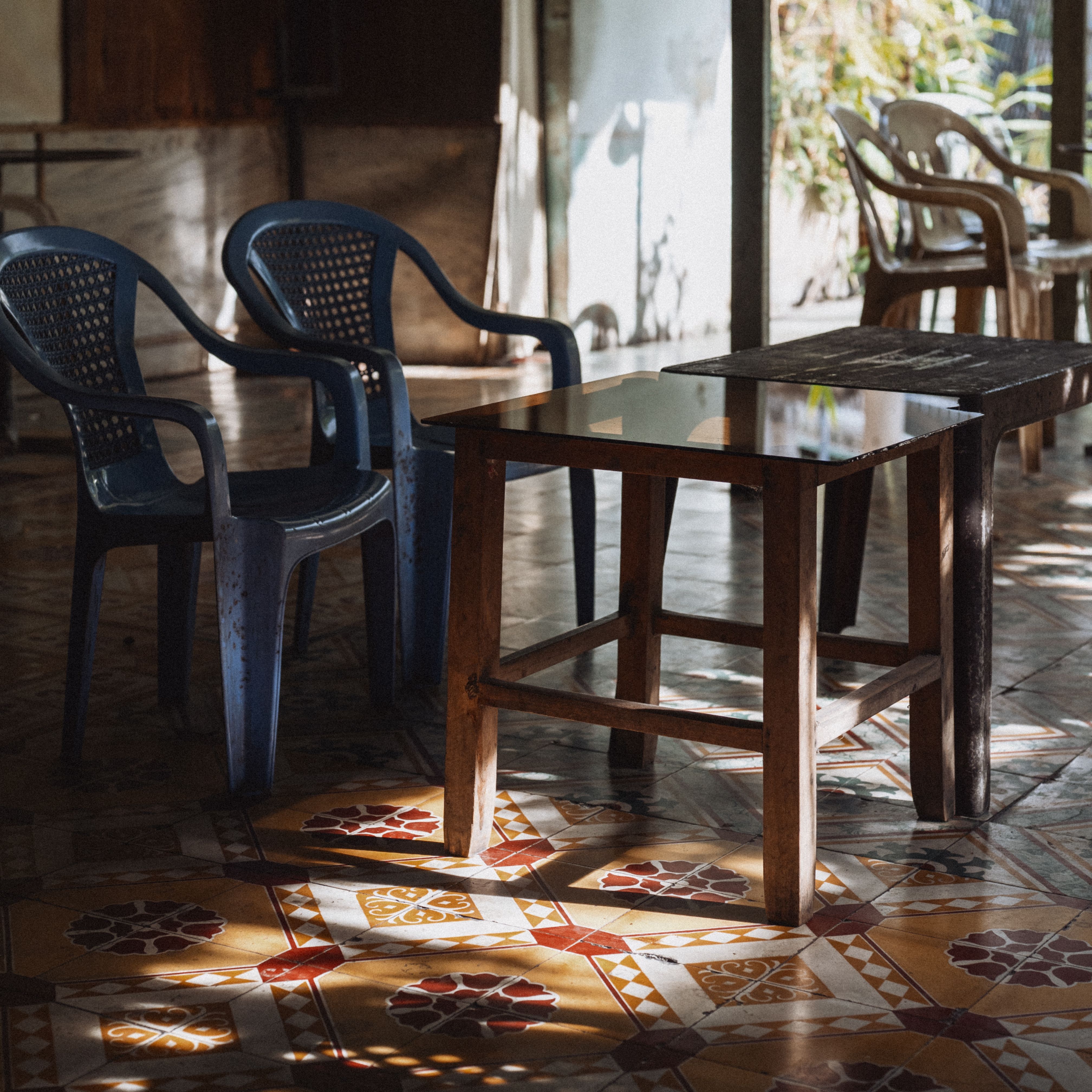 Warm and inviting outdoor seating area with sunlight casting beautiful patterns on the tiled floor.