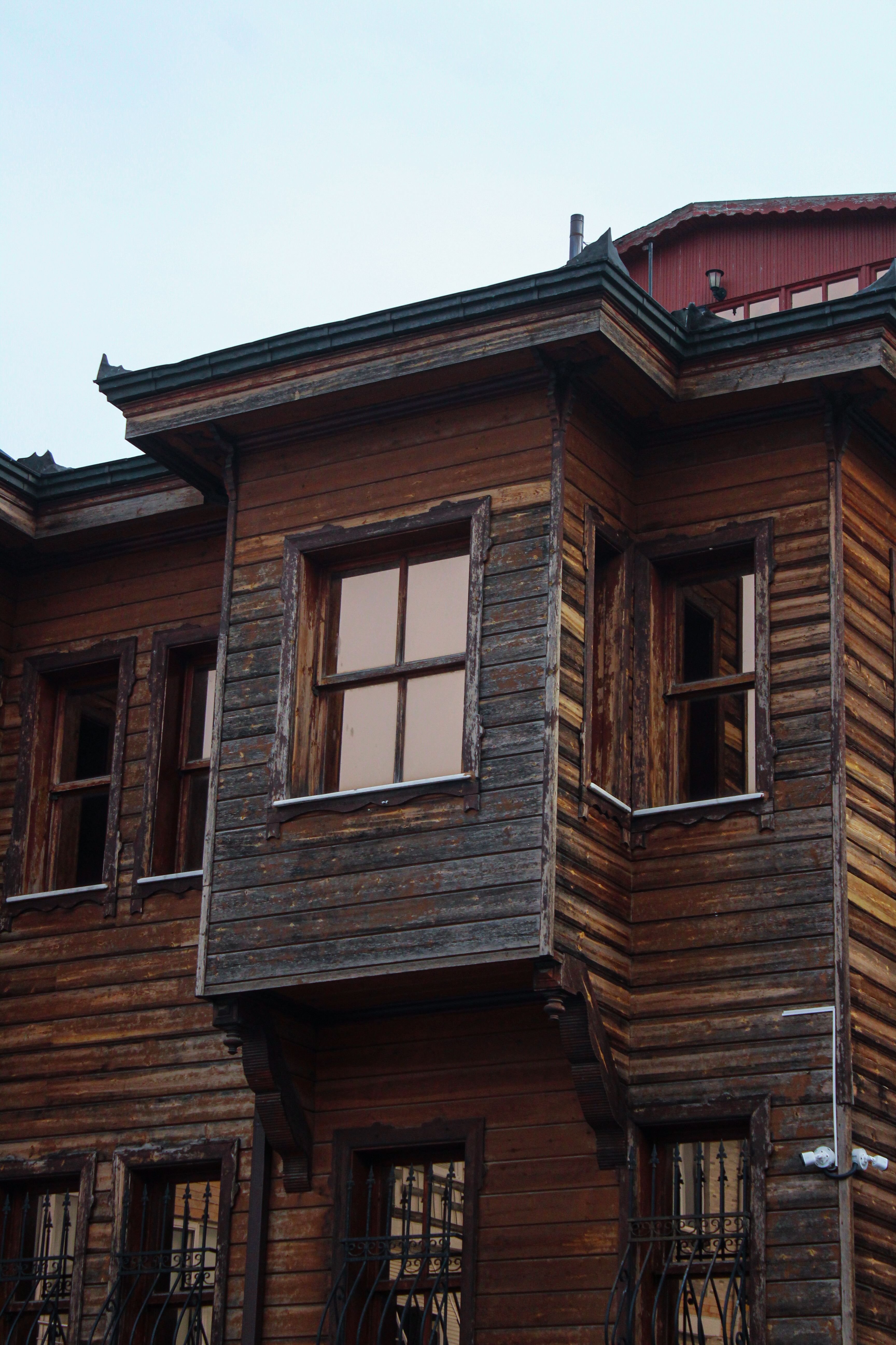 Close-up of a rustic wooden house facade featuring multiple windows and weathered texture.