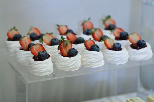 Free Delicious meringue desserts topped with fresh strawberries and blueberries, perfect for events and parties. Stock Photo
