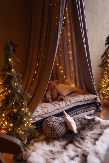 A warm and inviting indoor tent setup with a teddy bear, fairy lights, and plush decor for a serene ambiance.