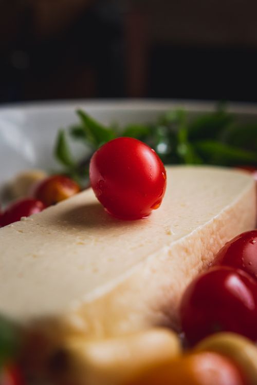 Free Delicious close-up of cheese topped with cherry tomatoes, perfect for a fresh appetizer. Stock Photo