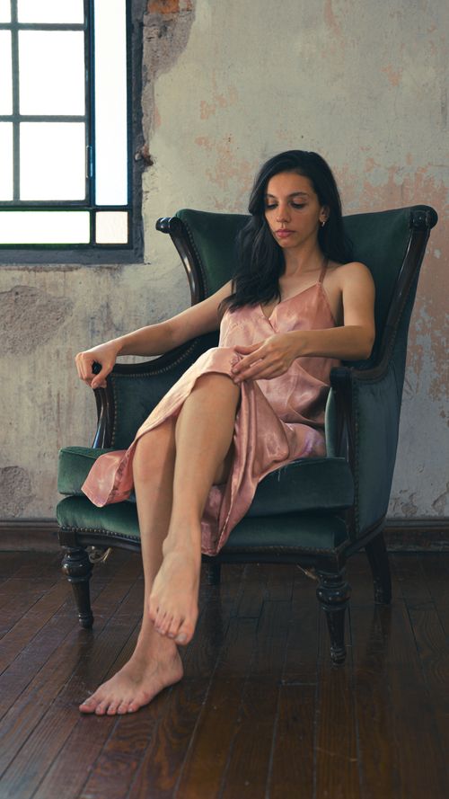 Free A serene adult woman sitting elegantly in a vintage armchair with natural lighting. Stock Photo