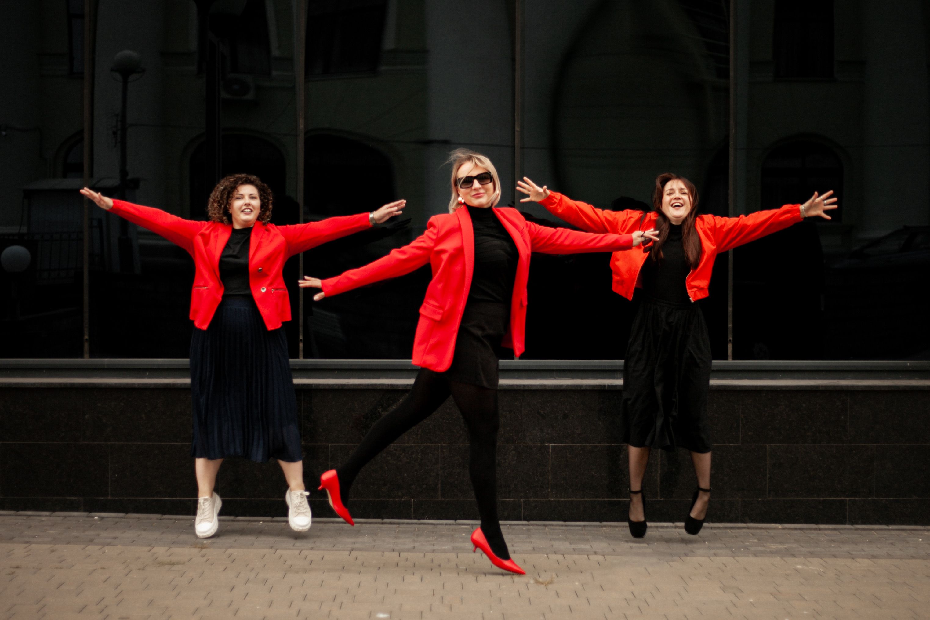 Women Joyfully Jumping in Red Attire Outdoors · Free Stock Photo
