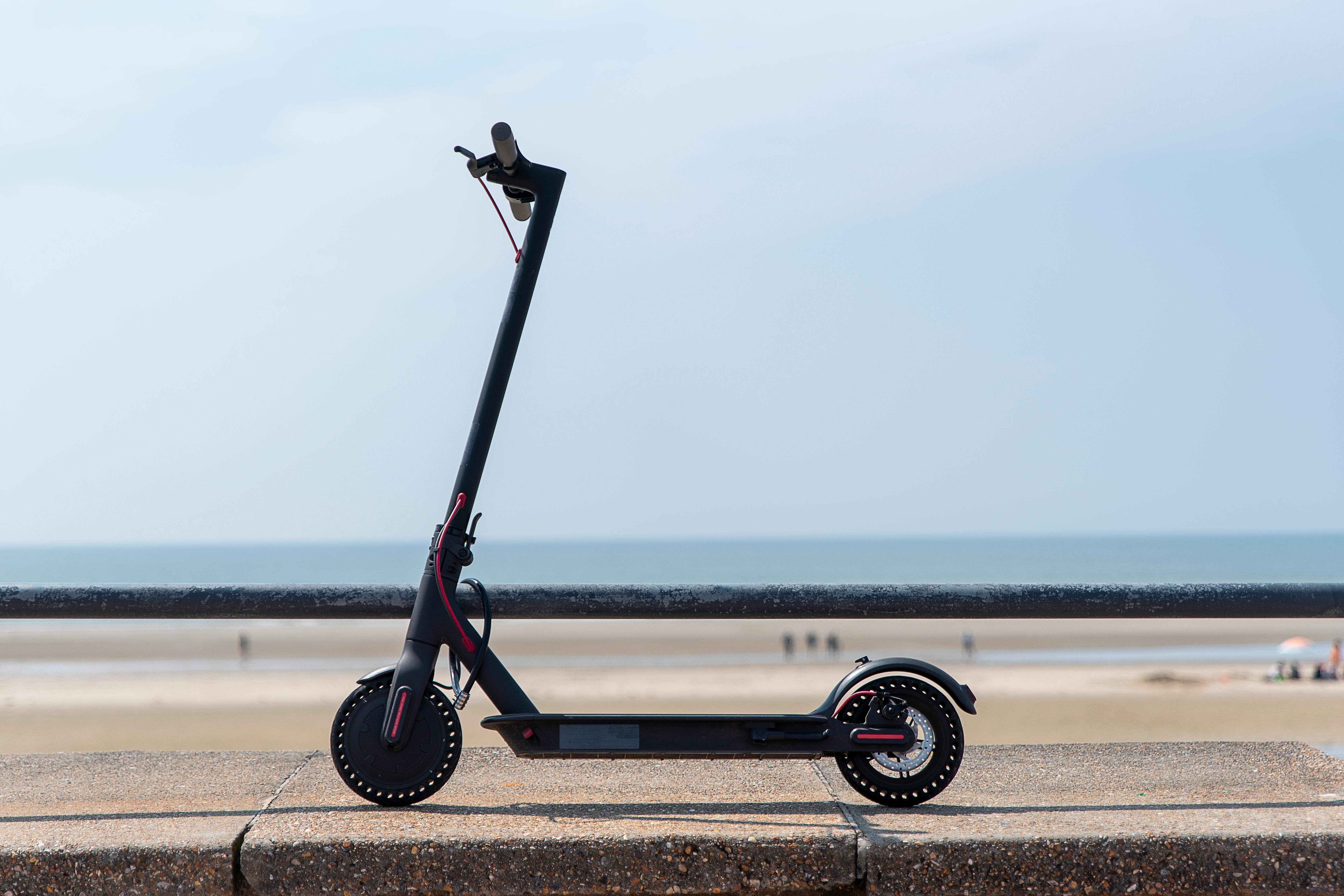 Sleek electric scooter parked by a scenic beachside on a clear day.