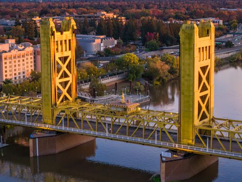 Free Aerial view of the iconic Tower Bridge over the Sacramento River during sunset with autumn foliage. Stock Photo