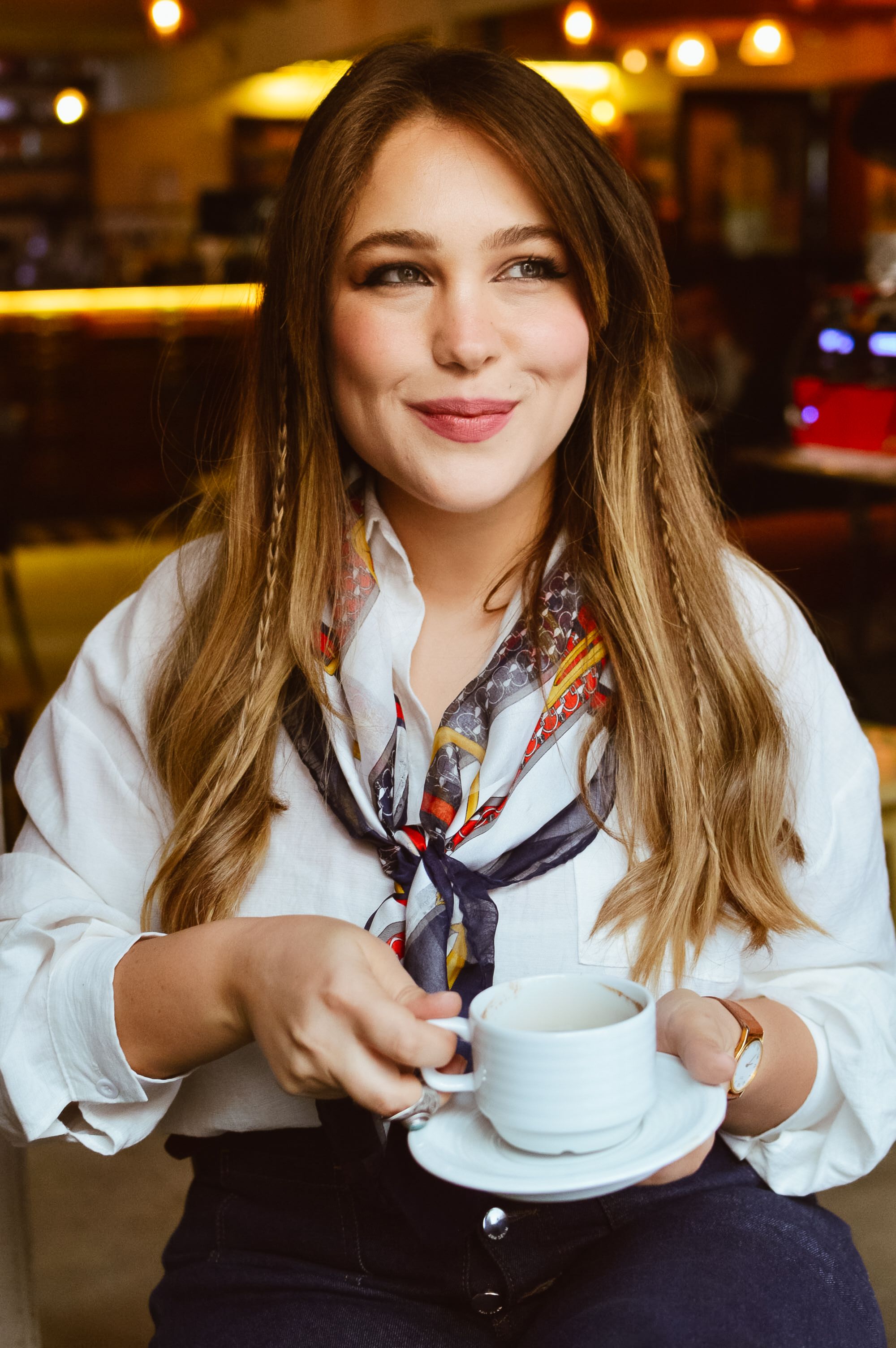 Smiling woman with coffee in cafe, exuding warmth and charm.