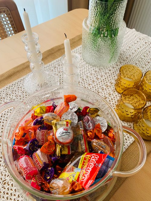 Free A glass basket full of assorted candies on a decorated table with candles and glassware. Stock Photo