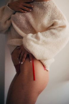 Close-up of a person wearing a cozy knit sweater with visible red lingerie detail.