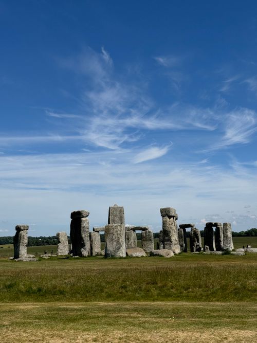 Free A wide shot of Stonehenge against a bright blue sky, capturing its ancient majesty. Stock Photo