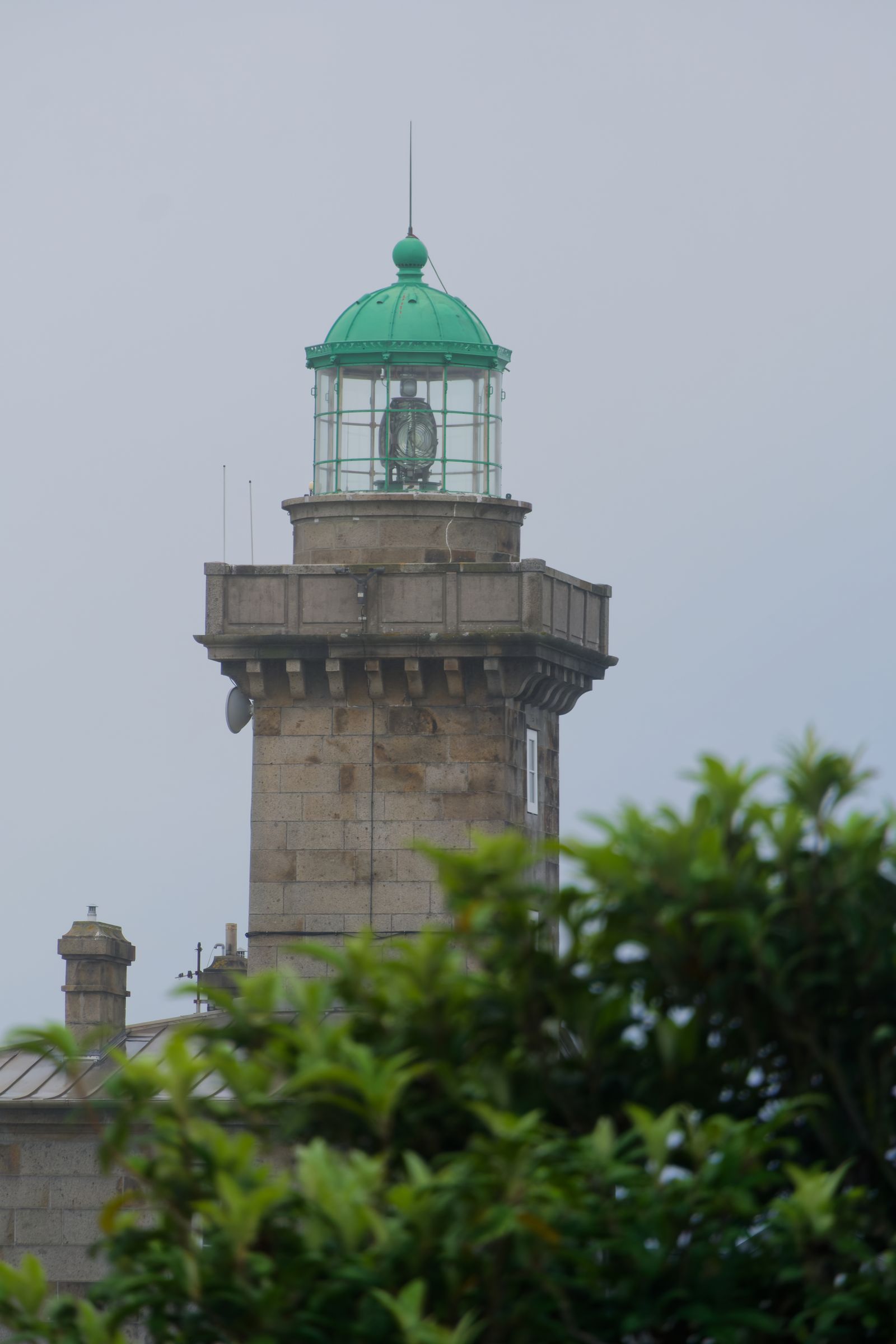 Phare en granit à lanterne verte derrière les arbres aux îles Chausey, France