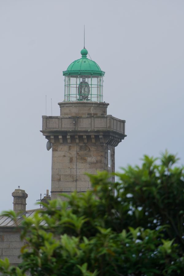 Phare en granit à lanterne verte derrière les arbres aux îles Chausey, France