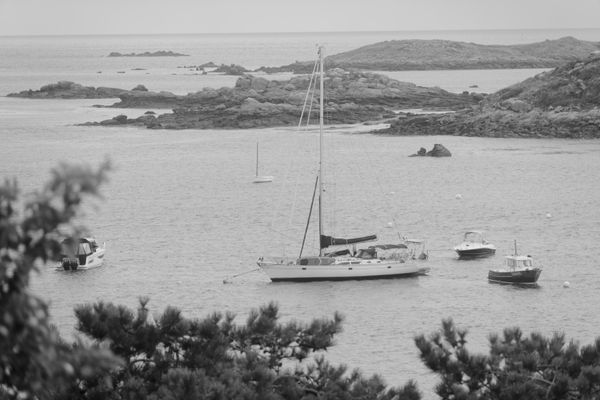 Vue en noir et blanc de voiliers au mouillage parmi les îlots rocheux de Chausey