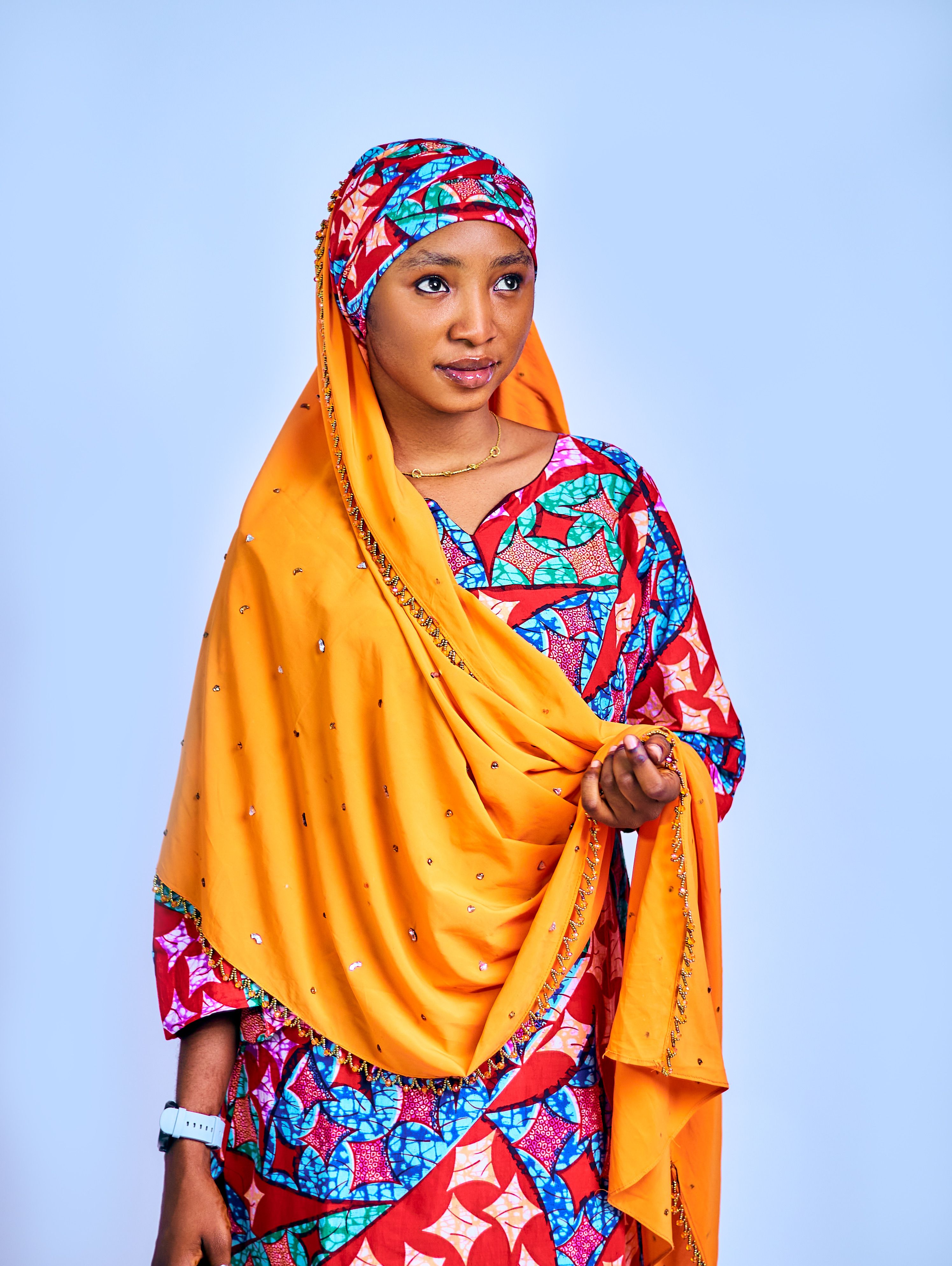 Portrait of a young woman wearing colorful traditional clothing with a neutral background.