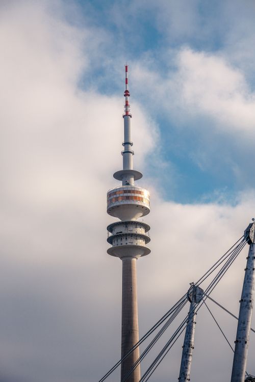Free Striking view of the Olympiaturm tower in Munich against a backdrop of clouds and blue sky. Stock Photo