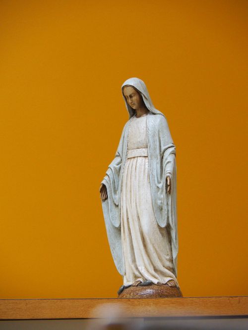 Free A detailed statue of the Virgin Mary set against a vibrant yellow backdrop. Stock Photo