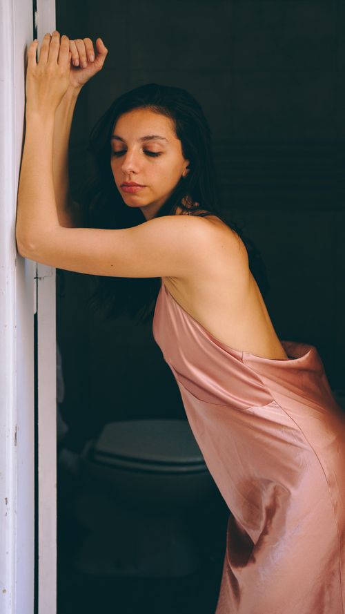 Free Elegant woman in a silky pink dress posing with grace indoors. Stock Photo
