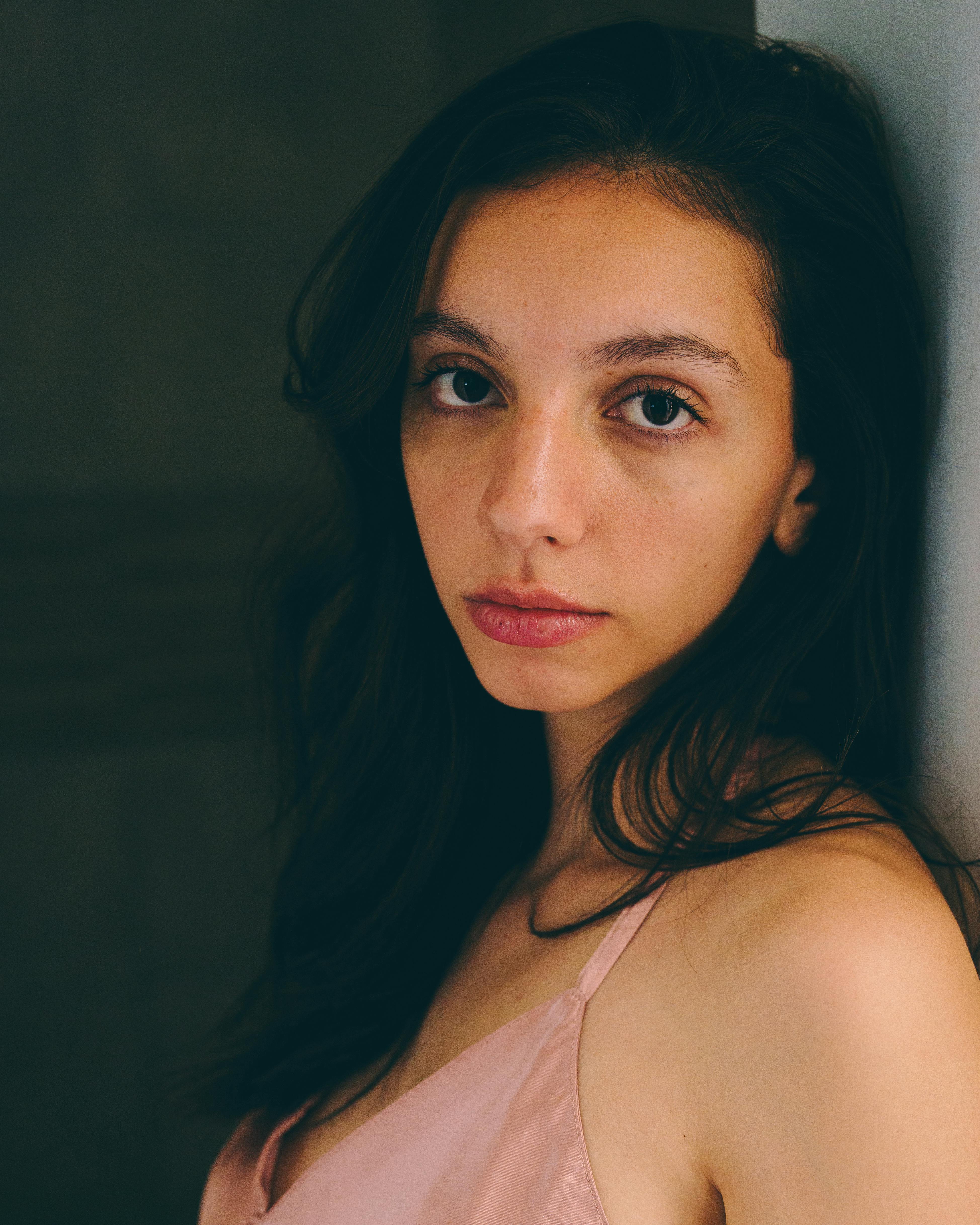 Close-up portrait of a young woman in soft, natural lighting indoors.