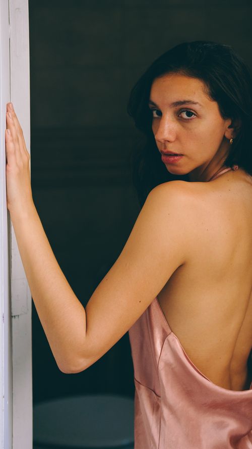 Free Back view of woman in silk dress looking back indoors. Elegant and intimate. Stock Photo