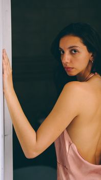Elegant woman in a satin dress posing indoors with a calm expression.