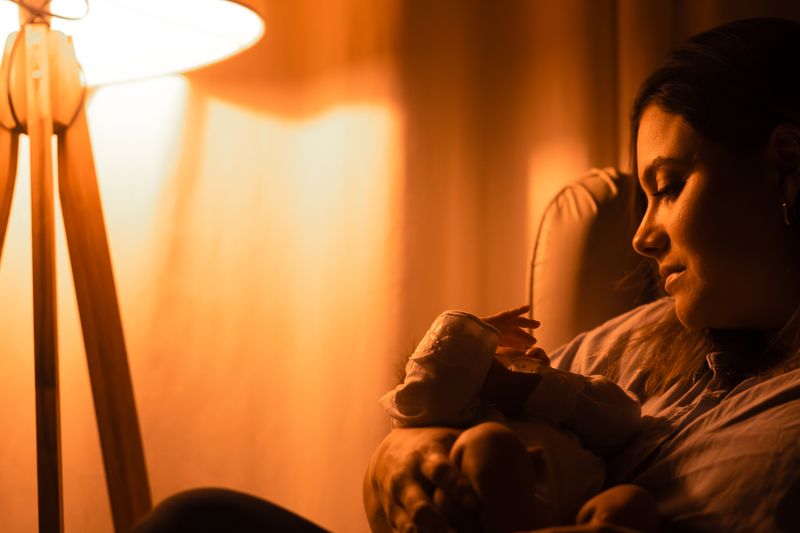 Madre contemplando a su bebé dormido bajo luz cálida