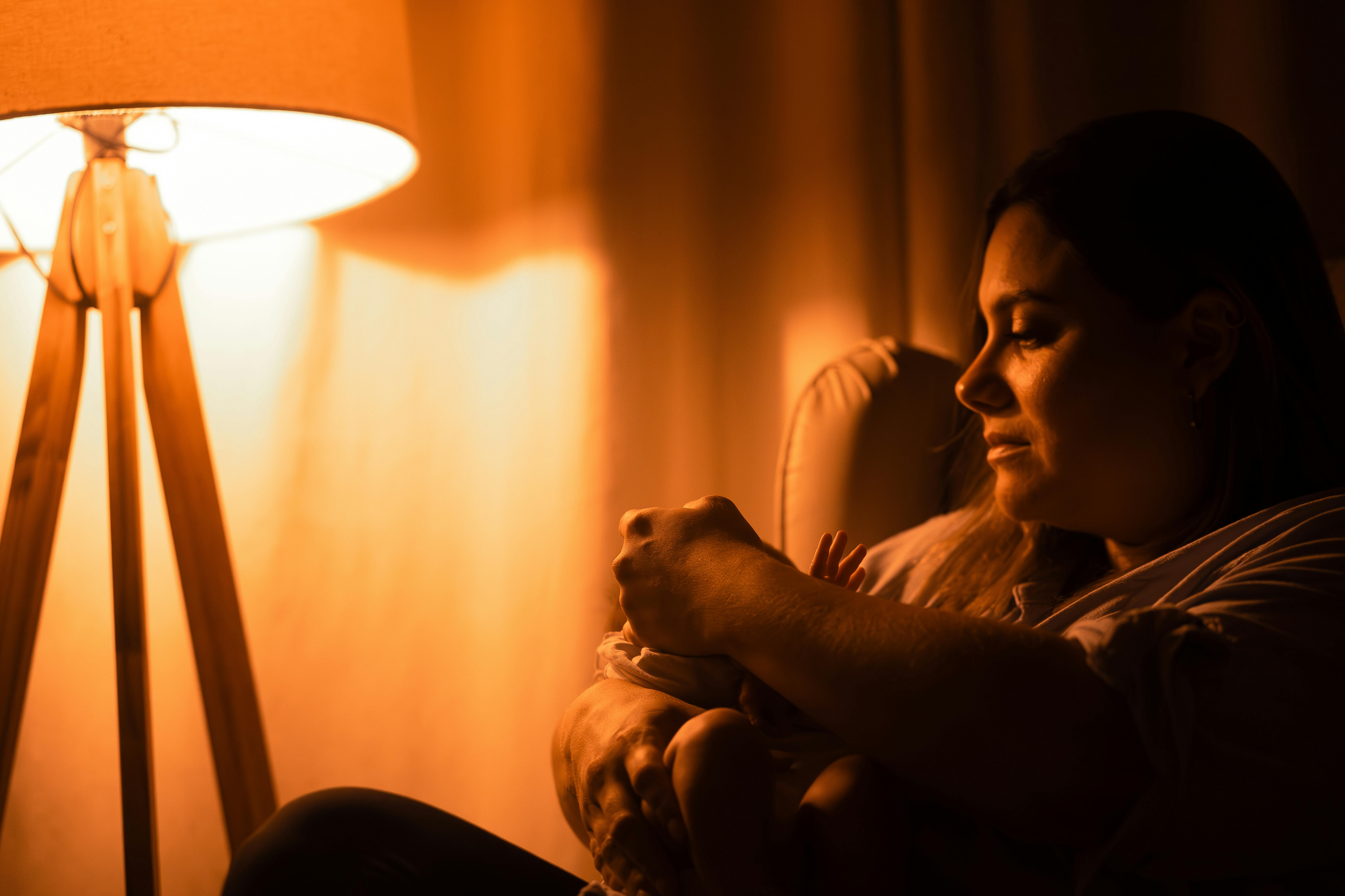 A mother tenderly cradling her infant in soft, warm lamp light.