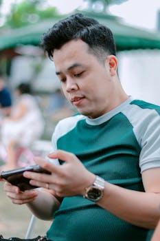 Confident man in casual attire using his smartphone outdoors, focused and relaxed.