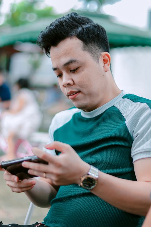Free Confident man in casual attire using his smartphone outdoors, focused and relaxed. Stock Photo