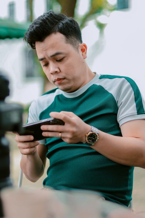 Free A man intently using his smartphone outside in a casual setting. Stock Photo