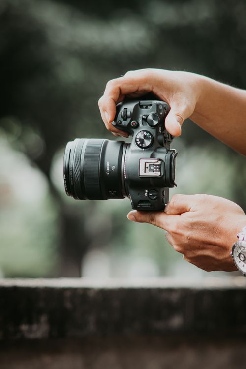Close-up of Photographers Hands Holding Camera Outdoors · Free Stock Photo