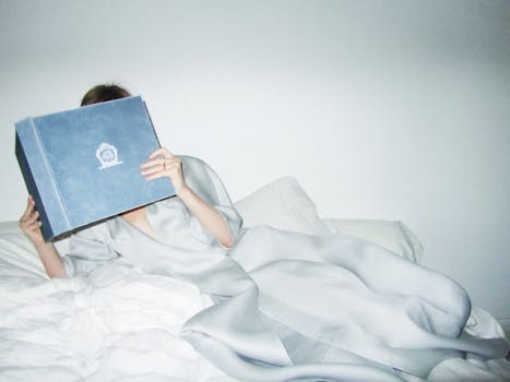 A person in a satin robe reading a book, creating a cozy and relaxing indoor scene.