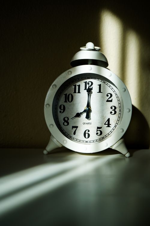 Free Classic vintage alarm clock casting shadow in sunlight indoors. Stock Photo